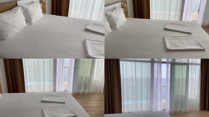 一个空荡荡的酒店房间，配有一张大床和一张白色干净的床，从酒店可以看到美丽的景色。