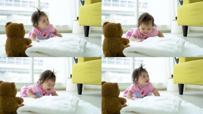 女婴看着泰迪熊，试图爬起来捡起来，但不能走，所以小女孩哭了，找妈妈帮忙，可爱的蹒跚学步的孩子学习享受