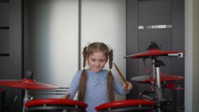 一个小女孩在家玩电子鼓。快乐的鼓棒女孩。玩电子鼓的小女孩