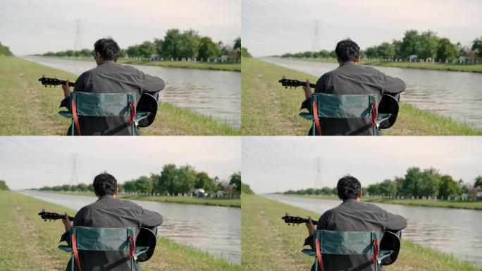 亚洲男人坐在自然的环境中弹吉他。