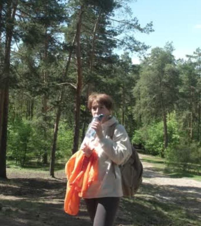 女人在森林中运动后正在喝水