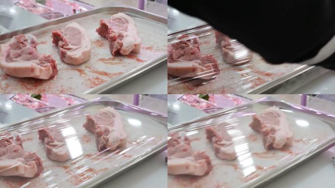 一家肉店的推销员用三个生猪肉和保鲜膜盖住了一个托盘。交易过程中的肉块按规定用食品聚乙烯覆盖