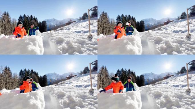 两个男孩在山上的雪堡垒里玩雪球
