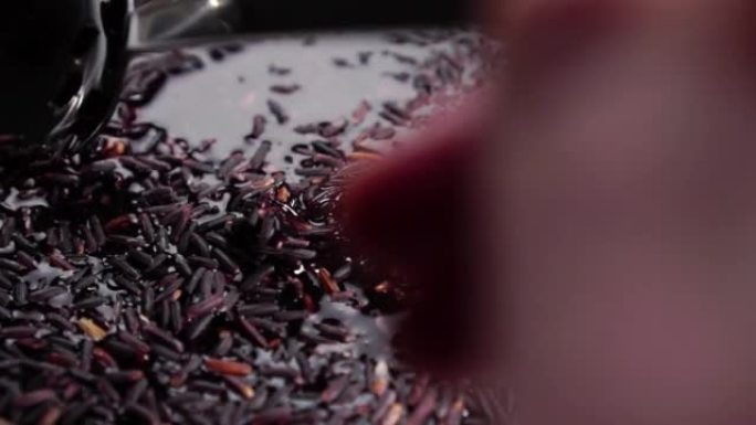 烹饪野生黑米。用勺子在水中搅拌湿谷物