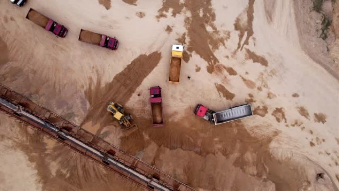 轮式装载机在露天矿的自卸车中装载沙子。露天矿土方工程前端装载机。