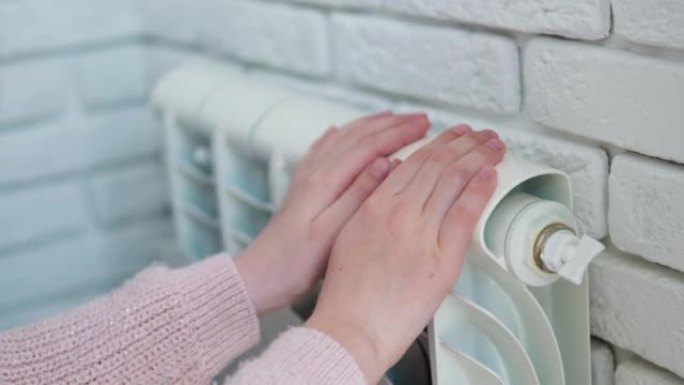 孩子在暖气片附近用手暖手。在供暖季节节省煤气。