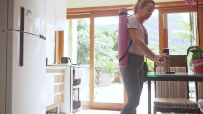 带运动垫的运动女人离开家去参加瑜伽课