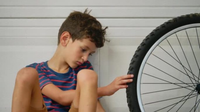 疲惫的男孩看着自行车轮胎