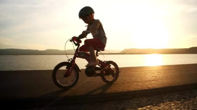 快乐的小男孩在日落时骑自行车。