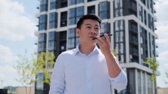 千禧一代中国商人盖伊在手机上激活虚拟助手。自信的韩国年轻人通过音频信息为社交网络中的商业伙伴或朋友录