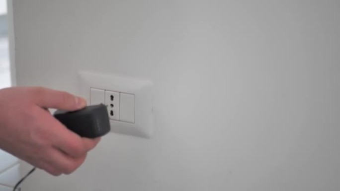 手动将黑色电源线电缆手机充电器图表插入墙上的电插座。准备连接插头。节能或降低成本的概念