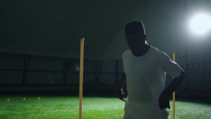 非裔美国少年夜间在室内大厅踢足球，慢动作中等肖像