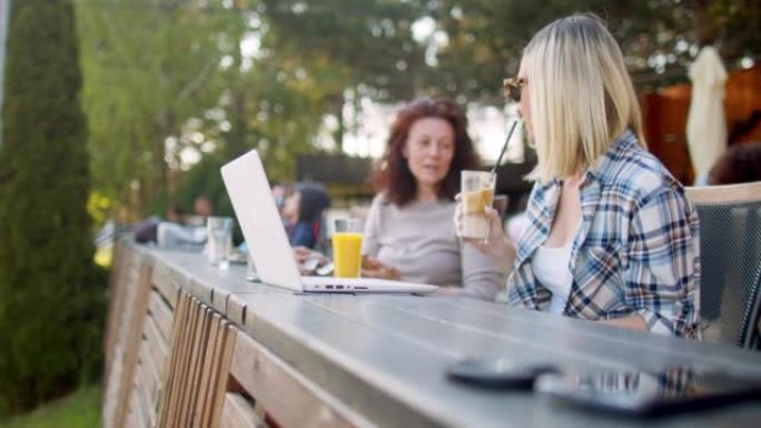 两名妇女在咖啡店放松但在笔记本电脑上工作