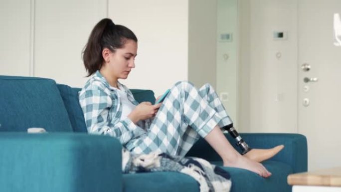 Serious woman with leg prosthesis texting by phone
