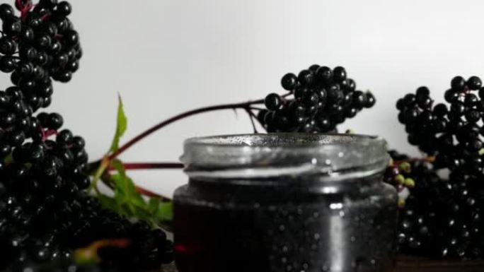 慢动作天然黑色接骨木浆果与挤压果汁在一个罐子，顺势疗法与有用的浆果治疗。木桌上的老树枝。