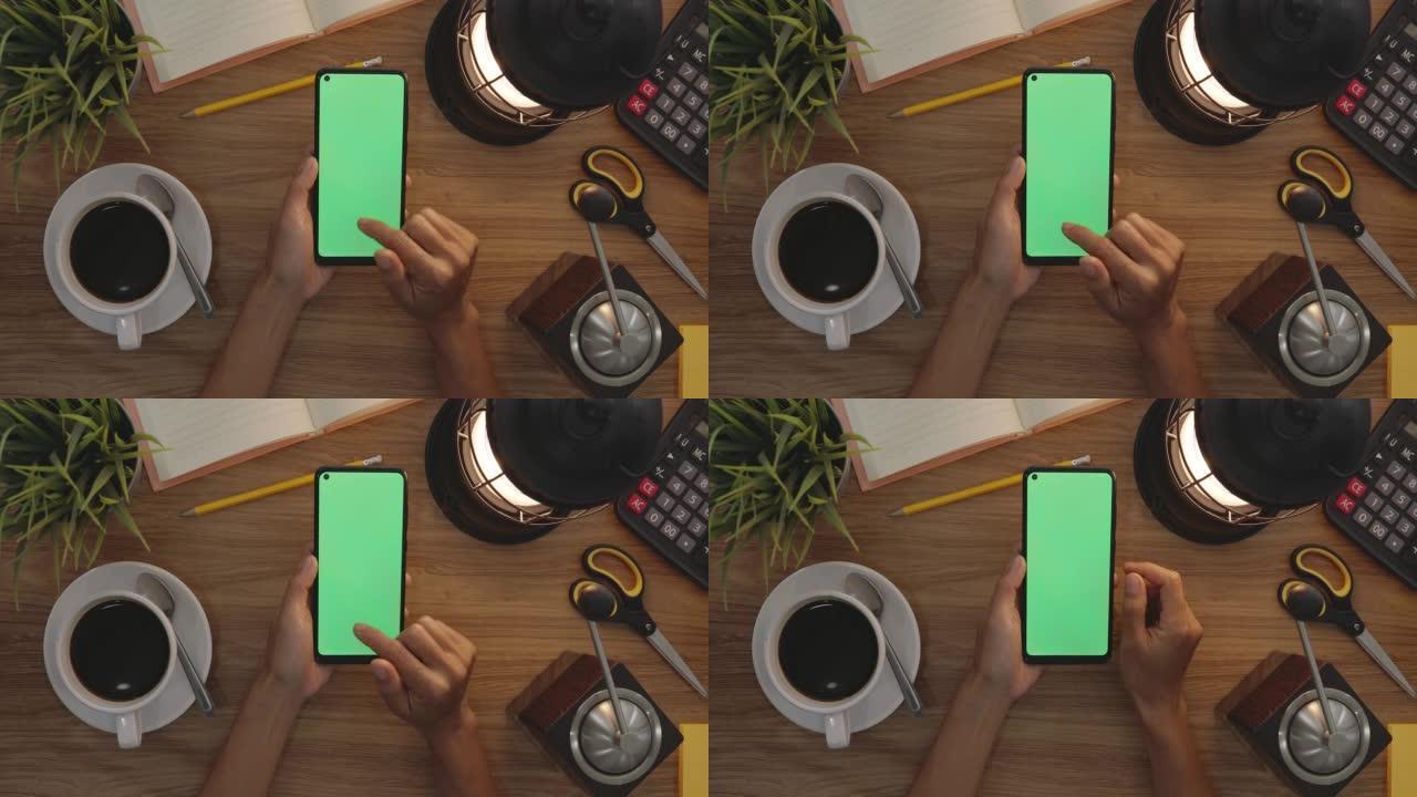 俯视图女人在智能手机的绿色屏幕上使用手指滑动。爱好表背景。色度键。绿屏手机。