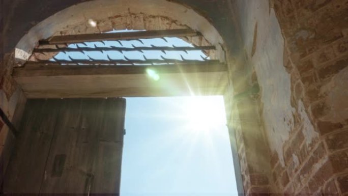 在一座破败的旧红砖教堂中，一扇带有格子残骸的门，云雾飞扬，阳光明媚。