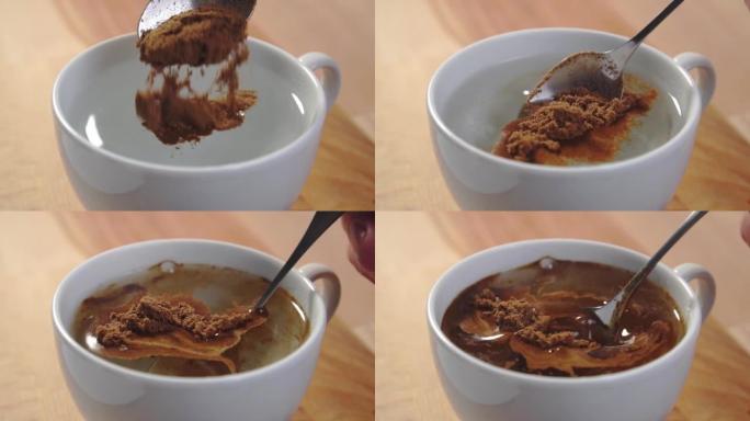 在木桌上的白杯热水中加入一茶匙速溶烘焙咖啡。粉末溶解和搅拌