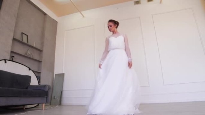 一个穿着白色婚纱的女孩摆姿势，挥舞着下摆。