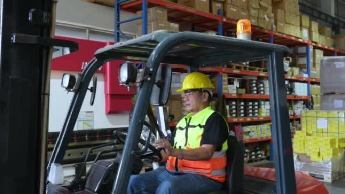 一名男性工人在仓库里驾驶叉车。把新来的人搬进仓库。
