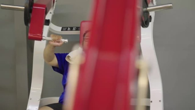 肥胖男子努力在健身俱乐部的侧向下拉机器上锻炼。