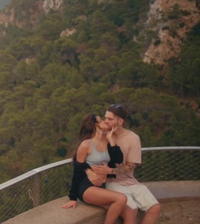 浪漫的夏天。夫妇在度假时参观一个景点，观看下面的风景。接吻垂直视频