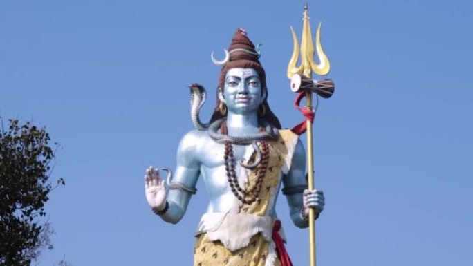 从不同角度看早晨明亮的蓝色天空背景的印度教神湿婆雕像