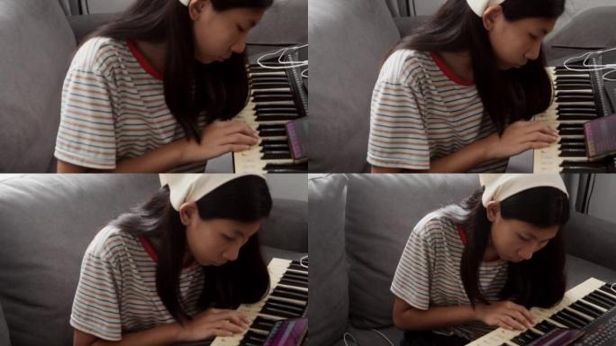 亚洲女孩在家里靠窗的沙发上通过移动应用学习弹奏键盘乐器，生活方式概念。