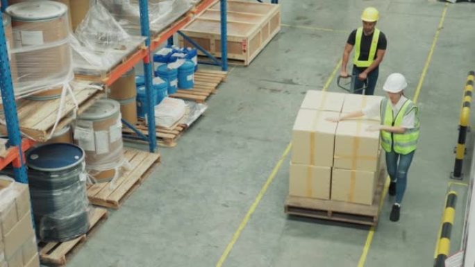 自上而下的镜头: 亚洲仓库工人男女移动推车塞满了商品在一个大型零售仓库的货架上。