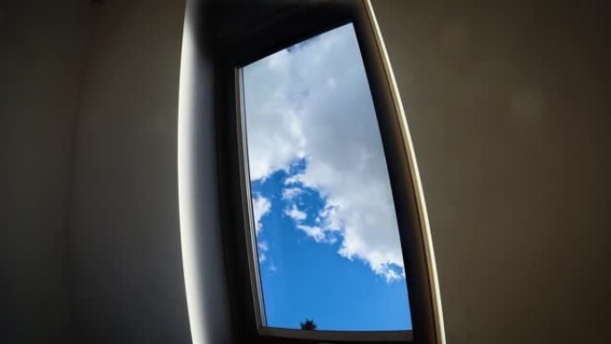 蓝色的天空，白色蓬松的云通过家庭窗户变成灰色的阴雨天气