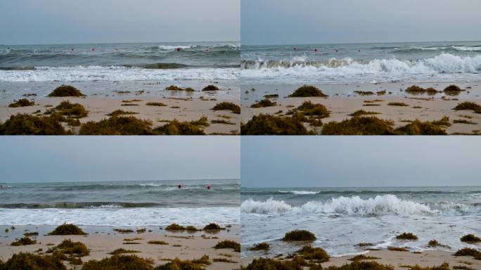 三亚大东海旅游区沙滩上浪花拍打海草上岸