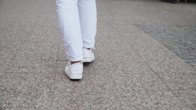 无法辨认的美女穿着白鞋的腿穿过城市