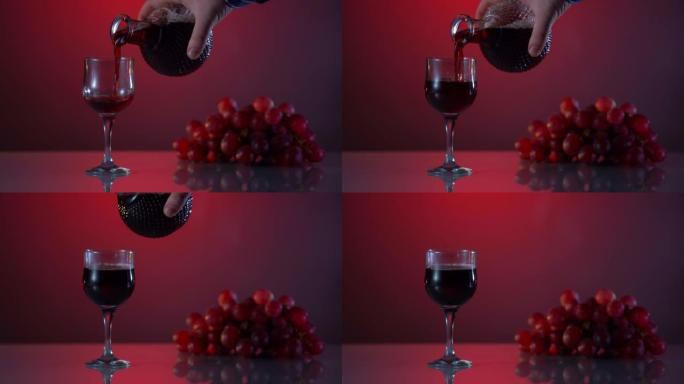 酒精。桌子上有新鲜葡萄的红藤。红色渐变背景。男子将酒倒入玻璃杯