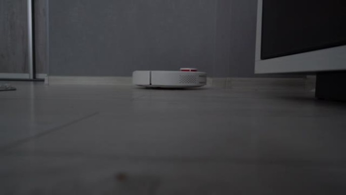 白色圆形机器人真空吸尘器清洁木地板上的灰尘。