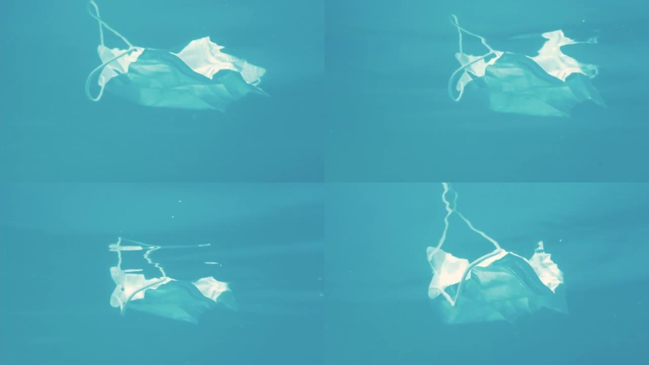 漂浮在海水中的无焦点防护面罩和手套的特写镜头。污染垃圾的概念