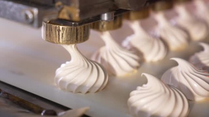 白色奶油棉花糖被挤压在移动的传送带上。特写。甜品制造自动化生产线。糖果概念。