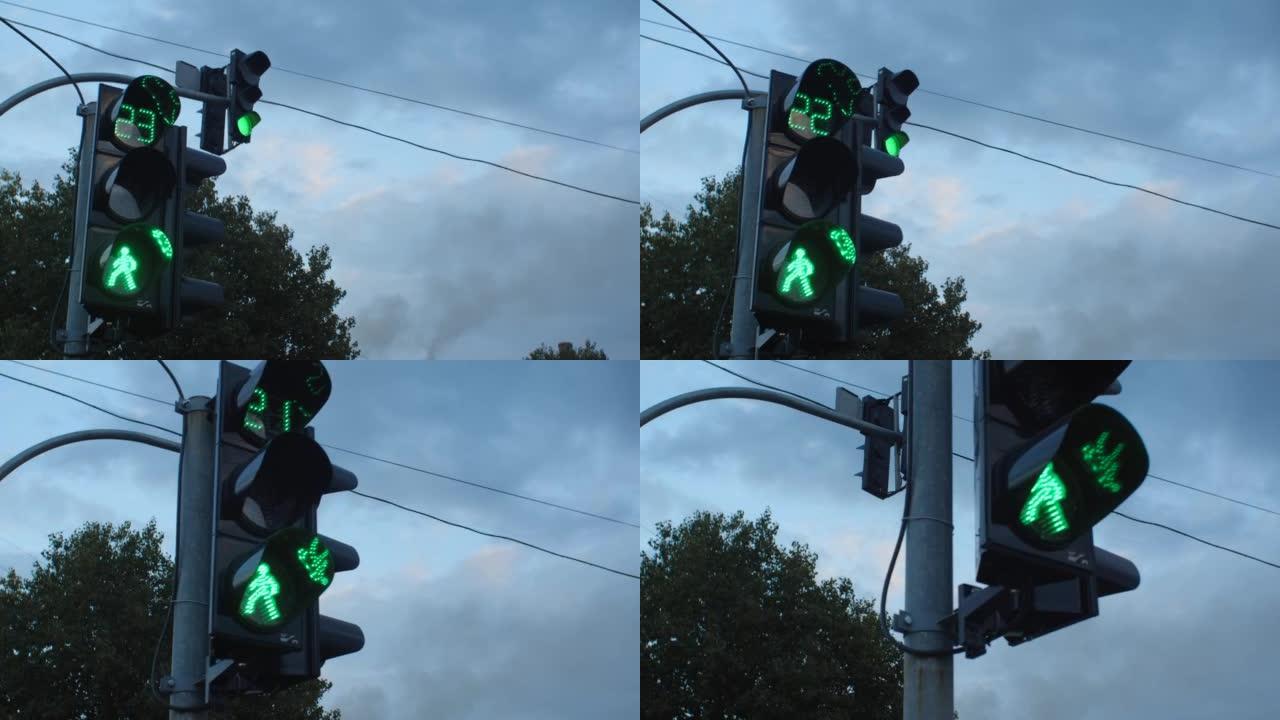 在多云的天空下，城市街道上的红绿灯特写镜头。红色变为绿色，熄灭并点亮。人行横道