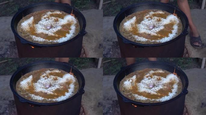 在大锅中火上煮抓饭。东方菜，米饭和肉。
