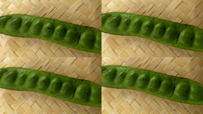 一根绿色的苦豆棒，放在编织的竹基上
