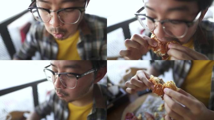饥饿的家伙的脸的特写镜头喜欢在午餐时咬和嚼汉堡。