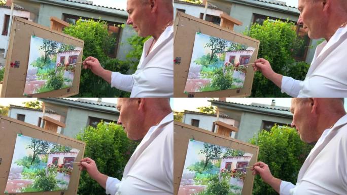 45-55岁的成年男性艺术家画了一幅画，看着他面前的房子一张纸，你已经可以看到窗户和绿色木材以及许多
