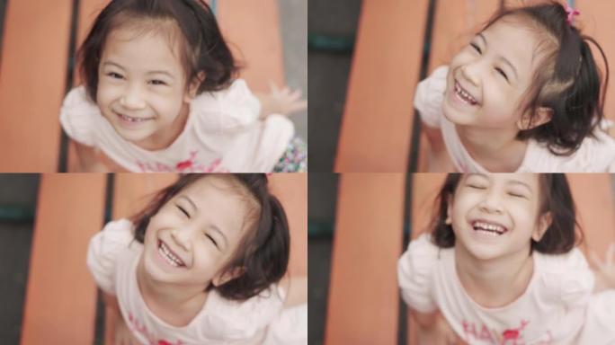 可爱的亚洲女孩的特写脸在夏天在学校背景下摆姿势，玩耍和看镜头，在微笑中表现出积极的情感，快乐和快乐。