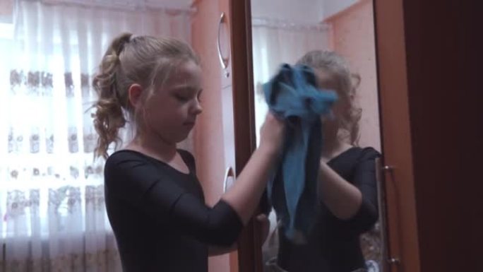 一个学龄女孩正在打扫她的公寓。她勤奋地擦拭壁橱镜子，帮助父母打扫房子。