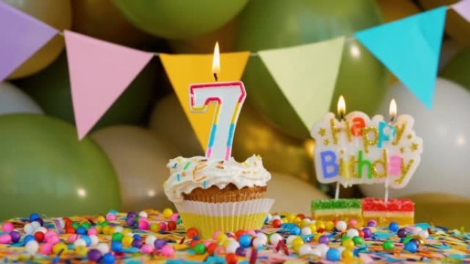 在转盘上向一个7岁的孩子致以美丽的生日问候，生日奶油蛋糕装饰蜡烛，生日装饰背景是气球