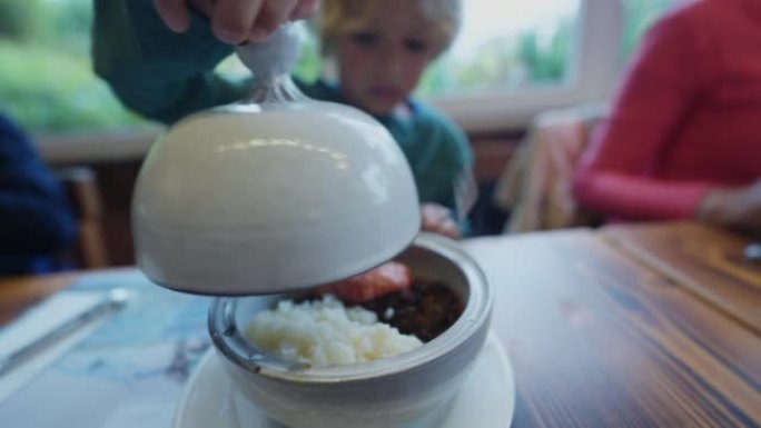 孩子露出食物的孩子坐在餐厅里拿着顶级菜