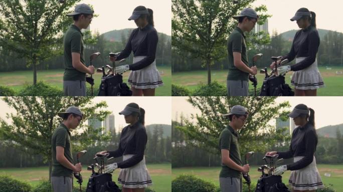 亚洲女高尔夫球手从高尔夫球袋中选择司机高尔夫俱乐部，教男孩如何在高尔夫球场上打高尔夫球
