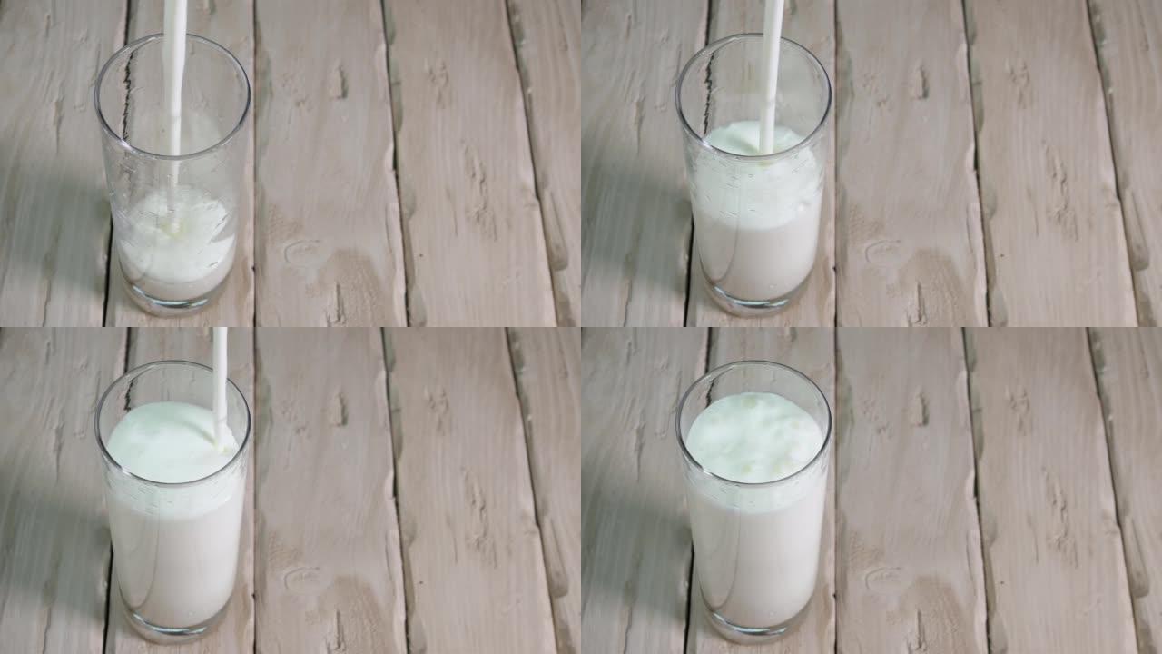 将酸奶倒入老式木板上的玻璃杯中。透明玻璃杯中的牛奶饮料