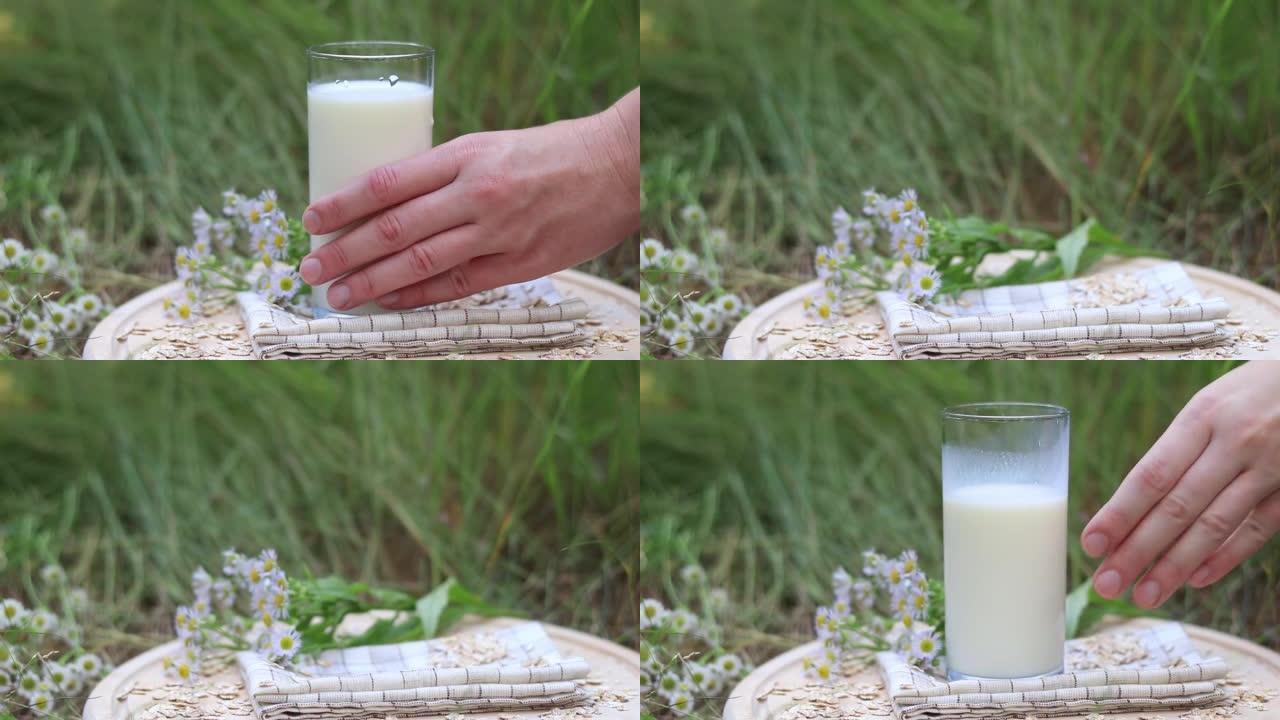 喝高杯中的牛奶。一个女人的手从一个木托盘里拿出一杯牛奶，然后放回去