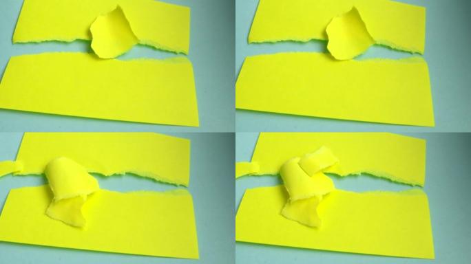 4k视频，小片黄纸落在躺在蓝色纸板背景上的撕纸横幅上，复制空间，概念广告