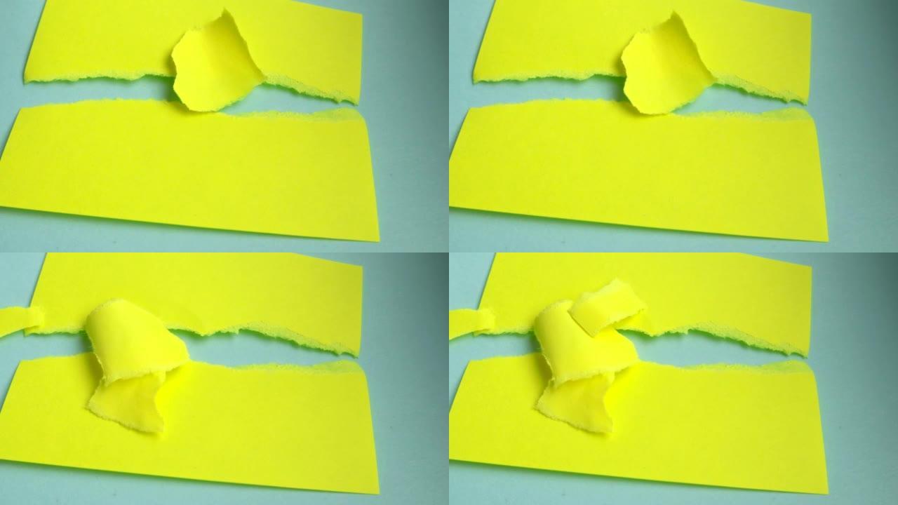 4k视频，小片黄纸落在躺在蓝色纸板背景上的撕纸横幅上，复制空间，概念广告